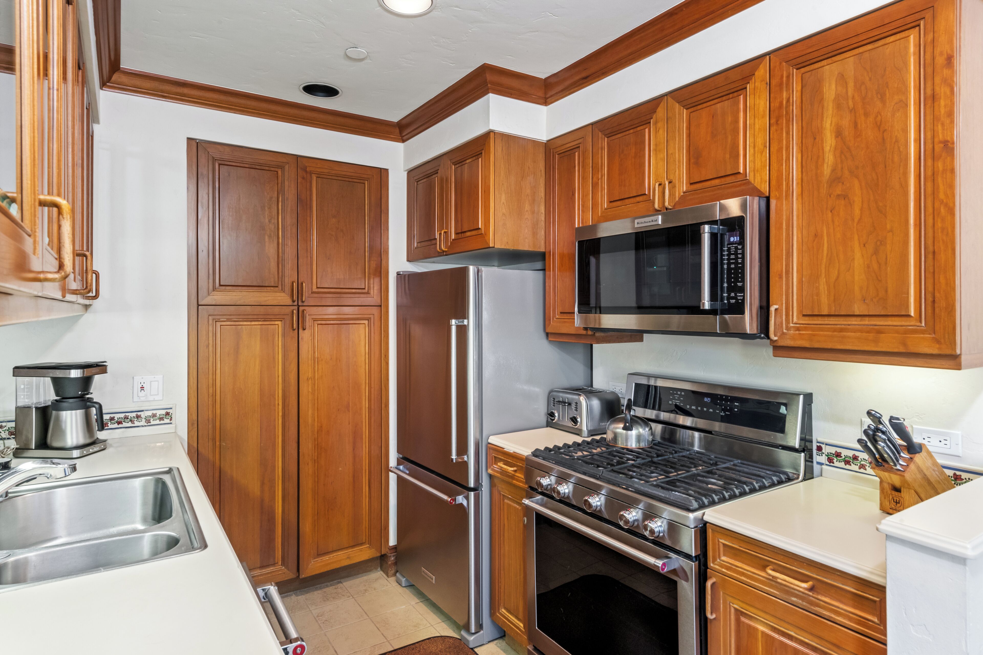 A kitchen with wooden cabinets, stainless steel appliances, a microwave, a stove, and a sink.