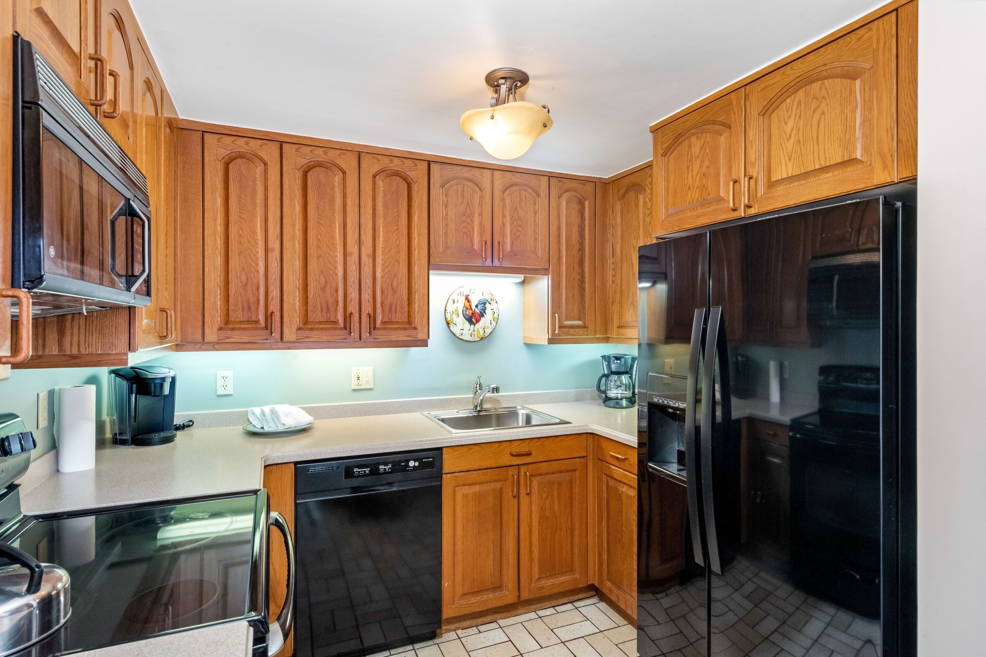 Una cocina con armarios de madera, lavavajillas, refrigerador y microondas.