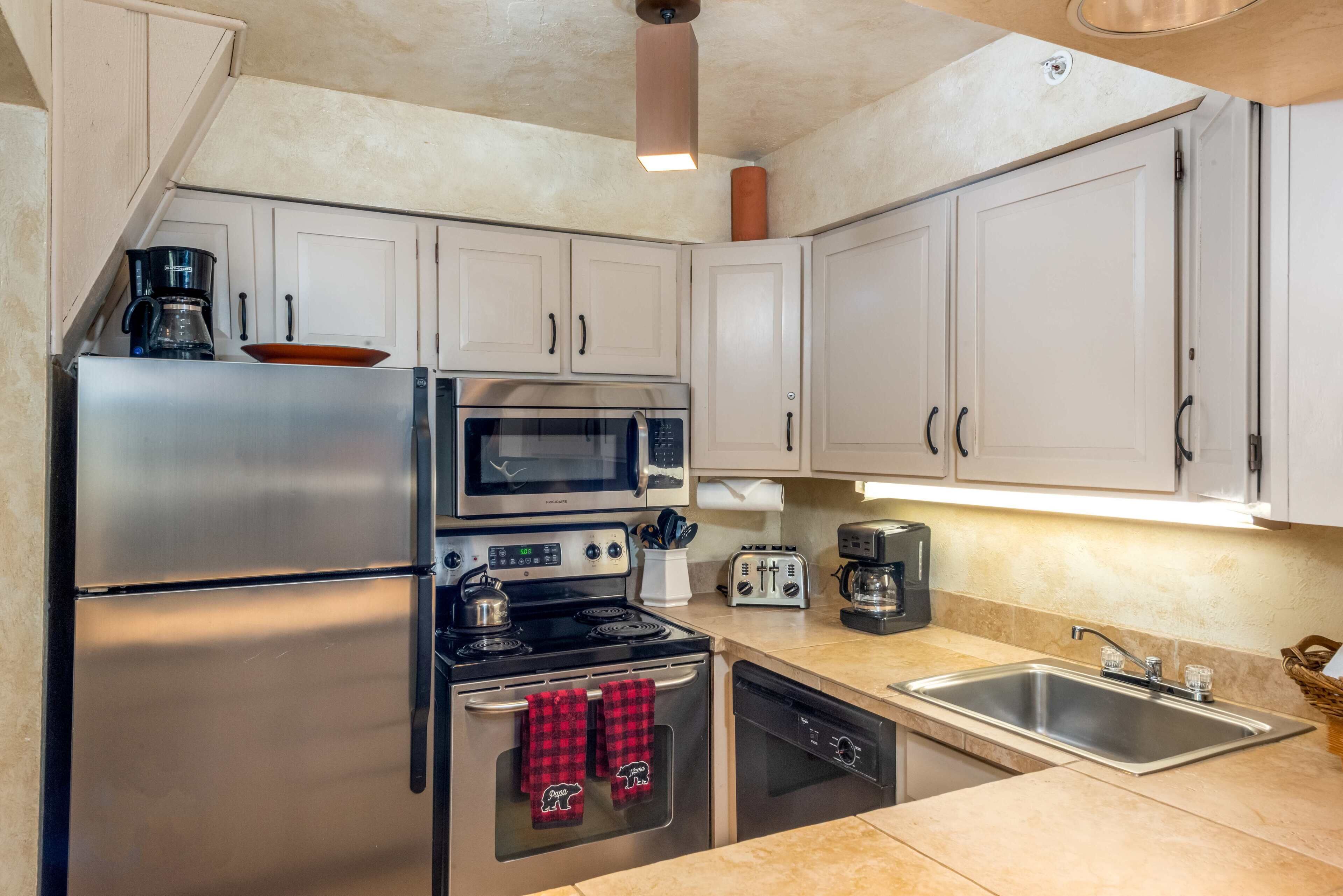 A compact kitchen with stainless steel appliances, a microwave, a toaster, and a dishwasher.
