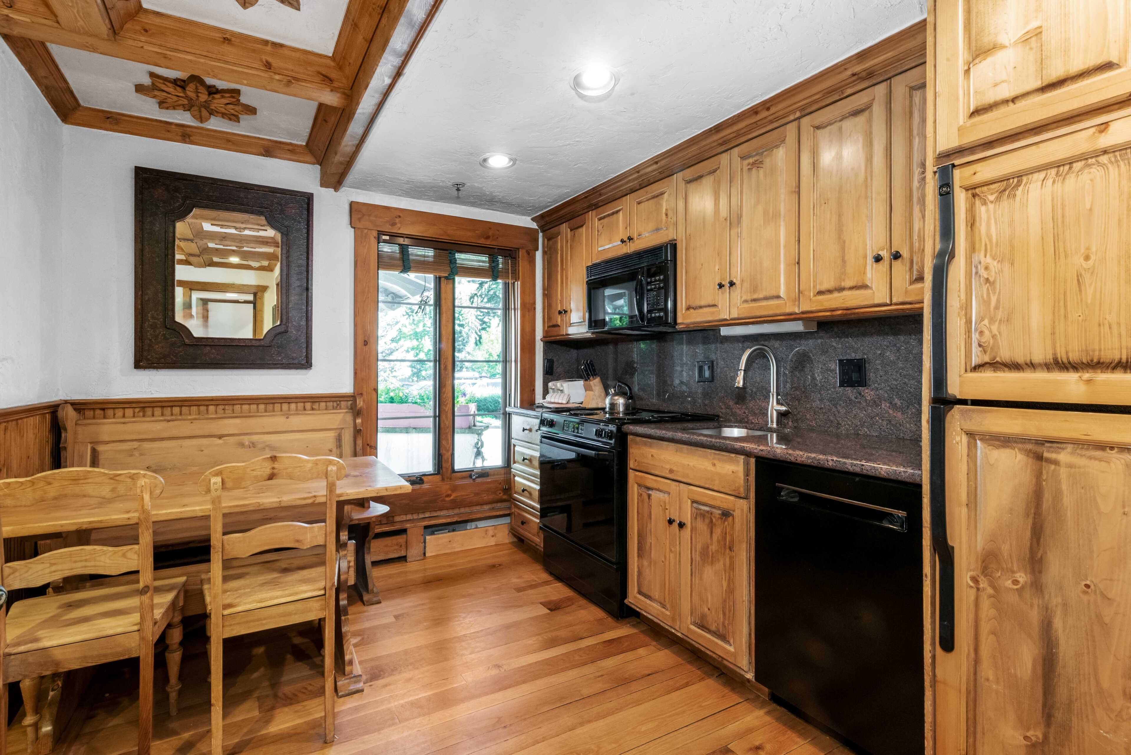 A kitchen with wooden cabinets, a microwave, a stove, and a sink.