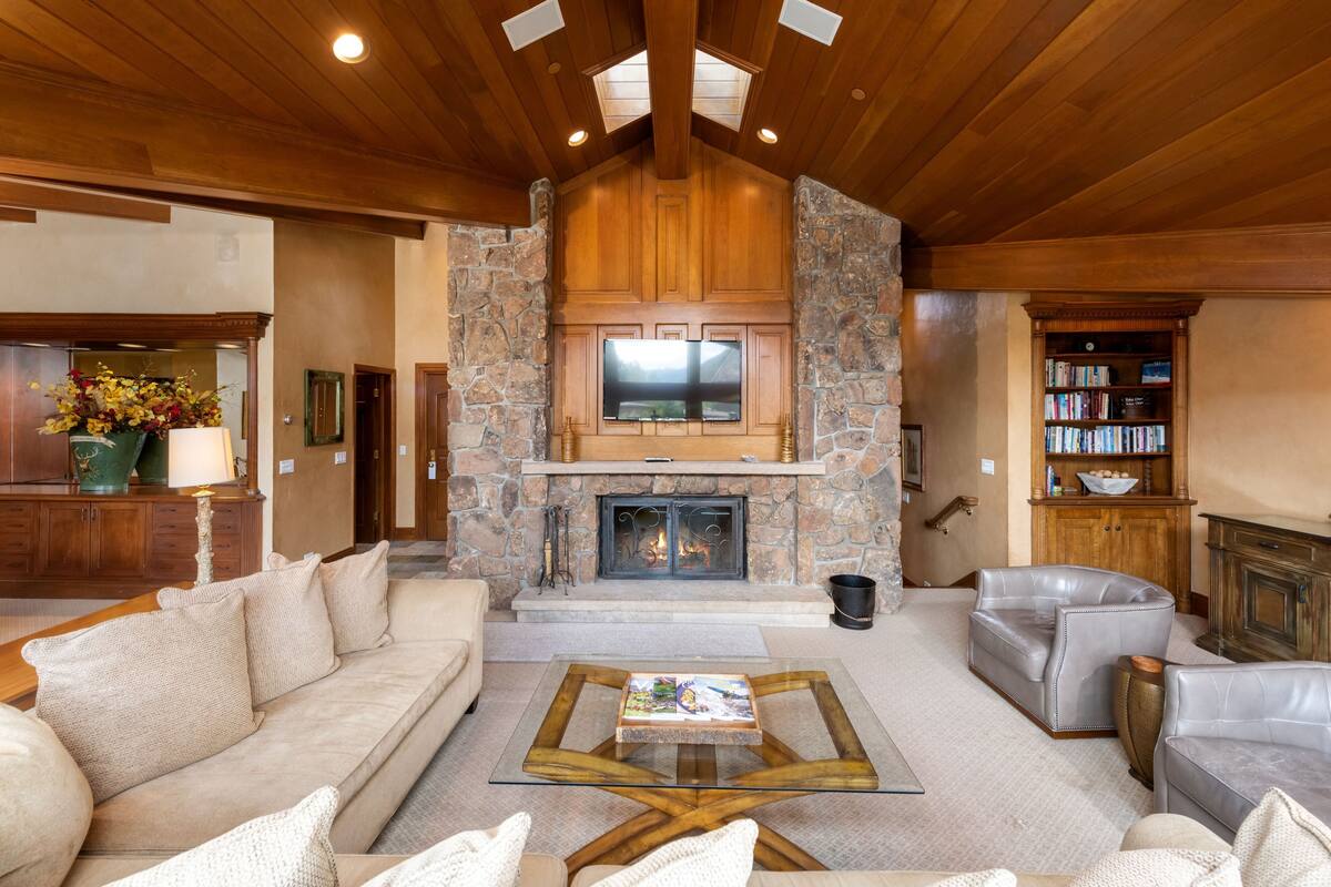 A spacious living room with a stone fireplace, leather sofas, and a glass coffee table.