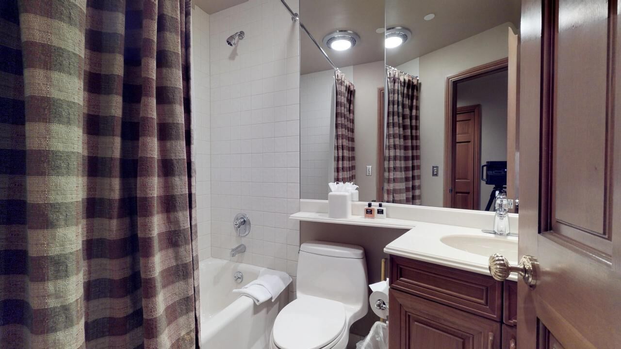 A bathroom with a white bathtub, a toilet, a sink, and a mirror.