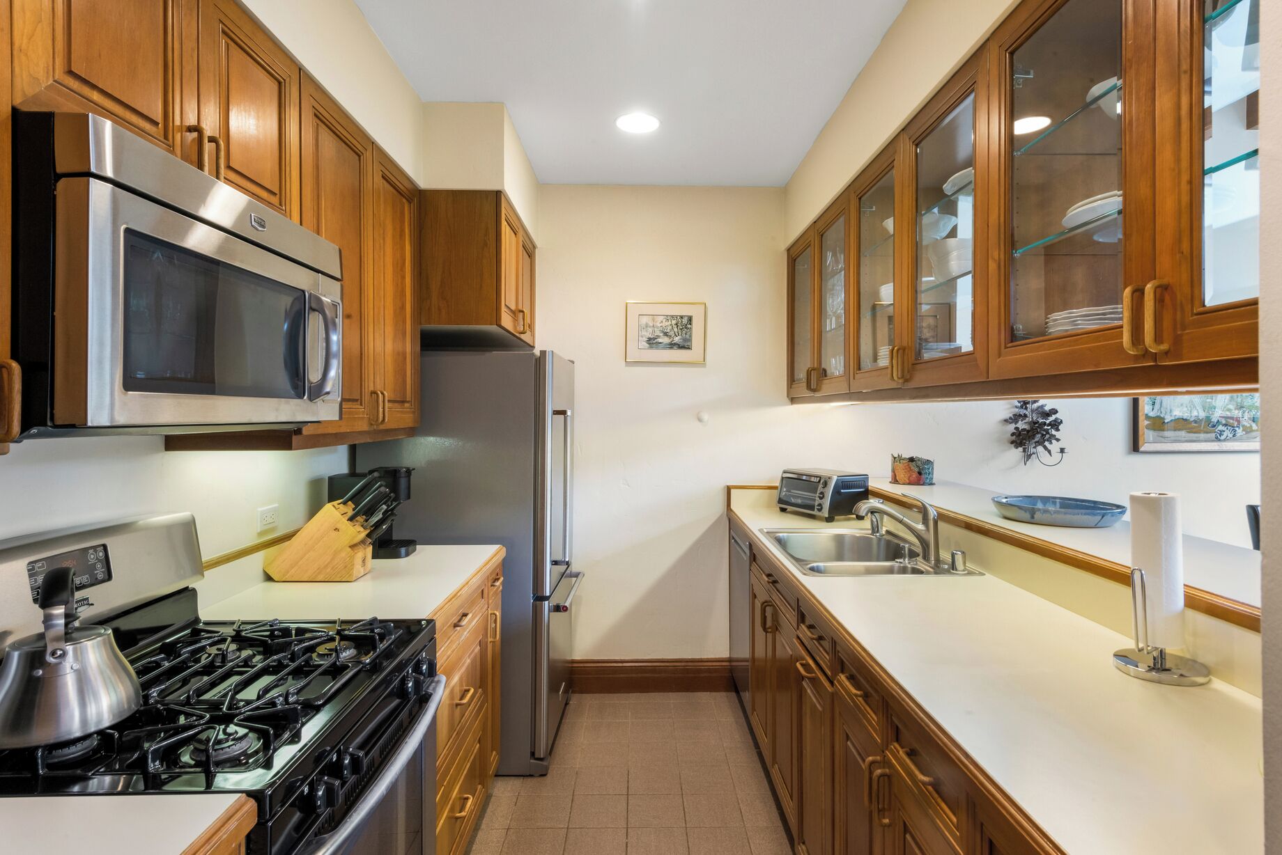Una cucina compatta con mobili in legno, elettrodomestici in acciaio inossidabile e piastrelle a mosaico.