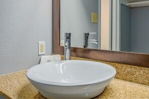 A bathroom with a white sink, a mirror, and a towel rack.
