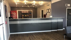 A reception area with a counter, a Coca-Cola sign, and a variety of snacks and beverages on shelves. - Extend a Suites & RV Park (Albuquerque)