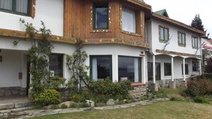 Ein zweistöckiges Haus mit einem grünen Dach, Holzverkleidung und einem Steinfundament.
