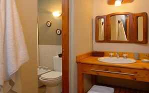 Une salle de bain avec un meuble-lavabo en bois, un évier, un miroir et des toilettes.
