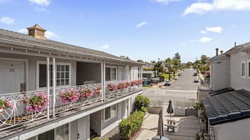 A two-story building with balconies, a covered outdoor seating area, and a street view.