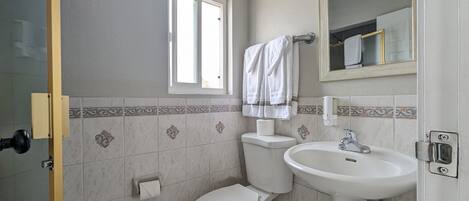 Uma casa de banho com sanita, lavatório e janela.