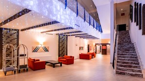 A spacious lobby with a staircase, red sofas, a cart, and decorative string lights. - Monte Baia Uludag (Bursa)