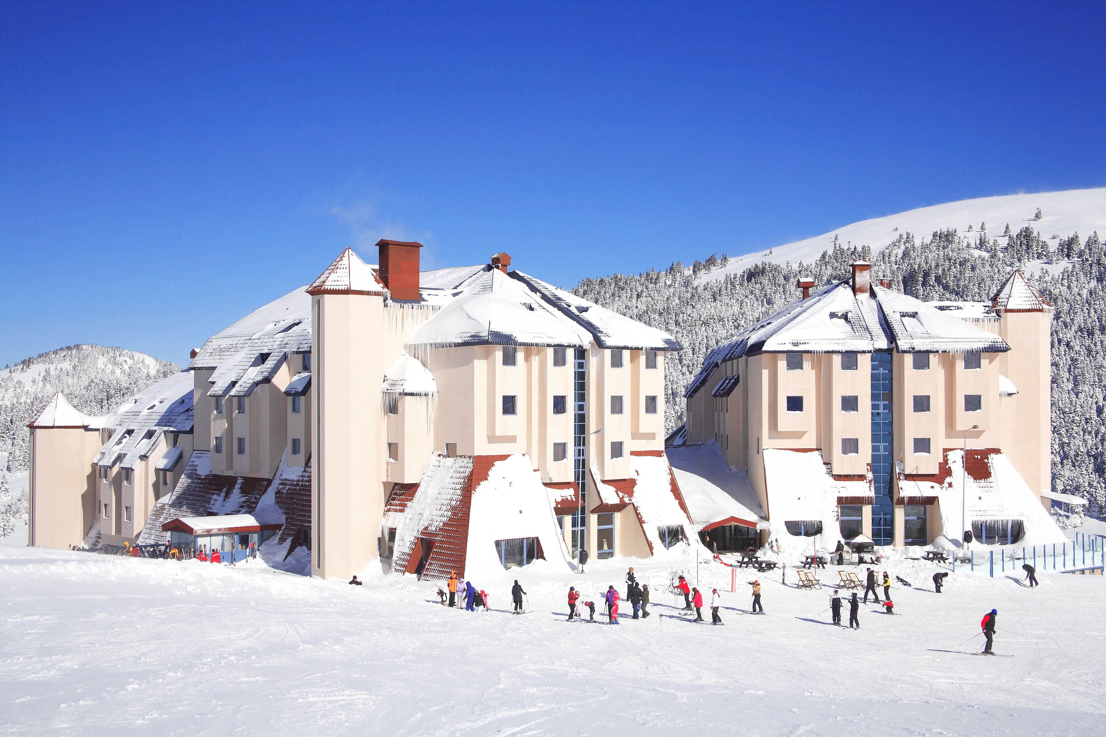 A large ski resort with multiple buildings, including a hotel with a red roof and a ski lift.