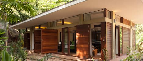 Una casa moderna con porche cubierto, puertas correderas de vidrio y jardín con senderos de piedra.