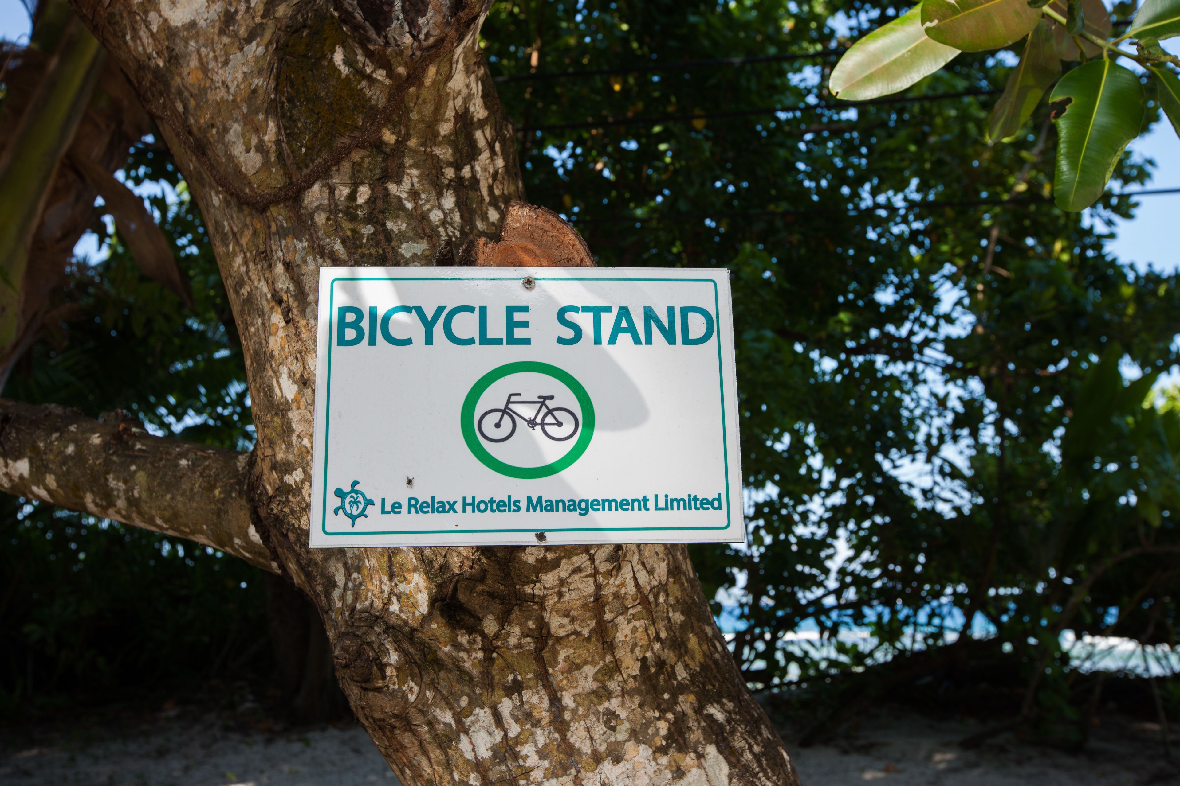 Un cartel en un árbol que indica un aparcamiento de bicicletas, gestionado por Le Relax Hotels Management Limited.