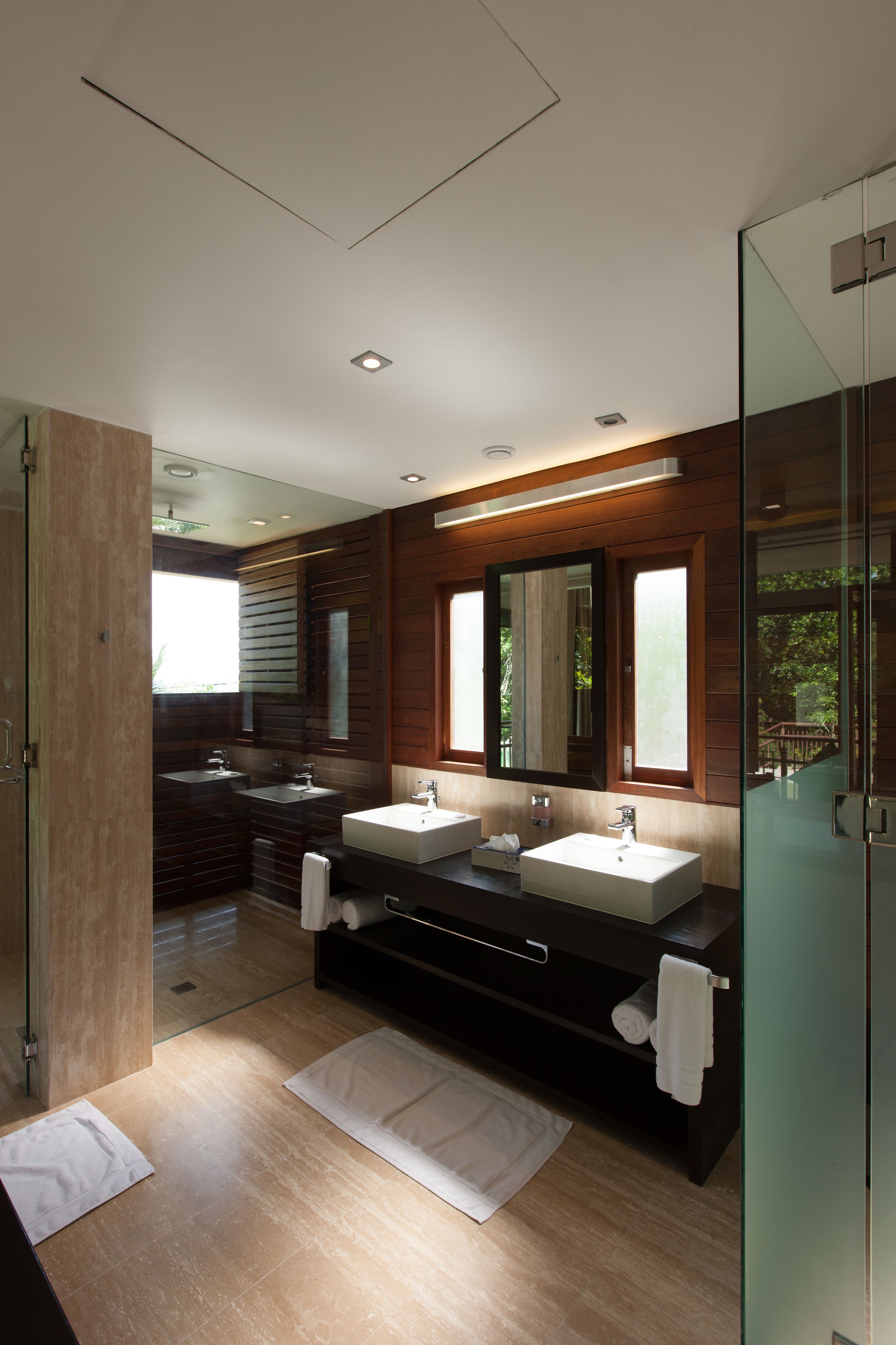 A modern bathroom with two sinks, a large mirror, and a glass shower enclosure.