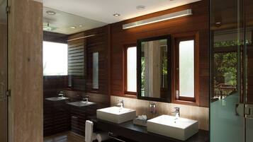A modern bathroom with two sinks, a large mirror, and a glass shower enclosure.