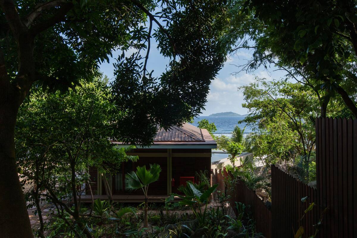 Uma cabana de madeira com vista para o mar e montanhas ao fundo.