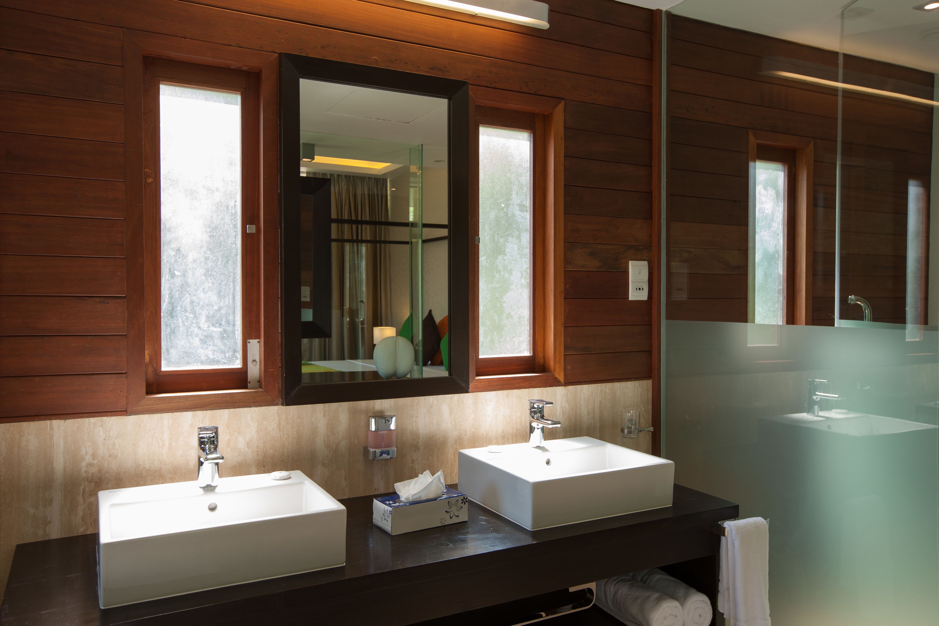 Un baño con dos lavamanos, paneles de madera y un espejo grande.