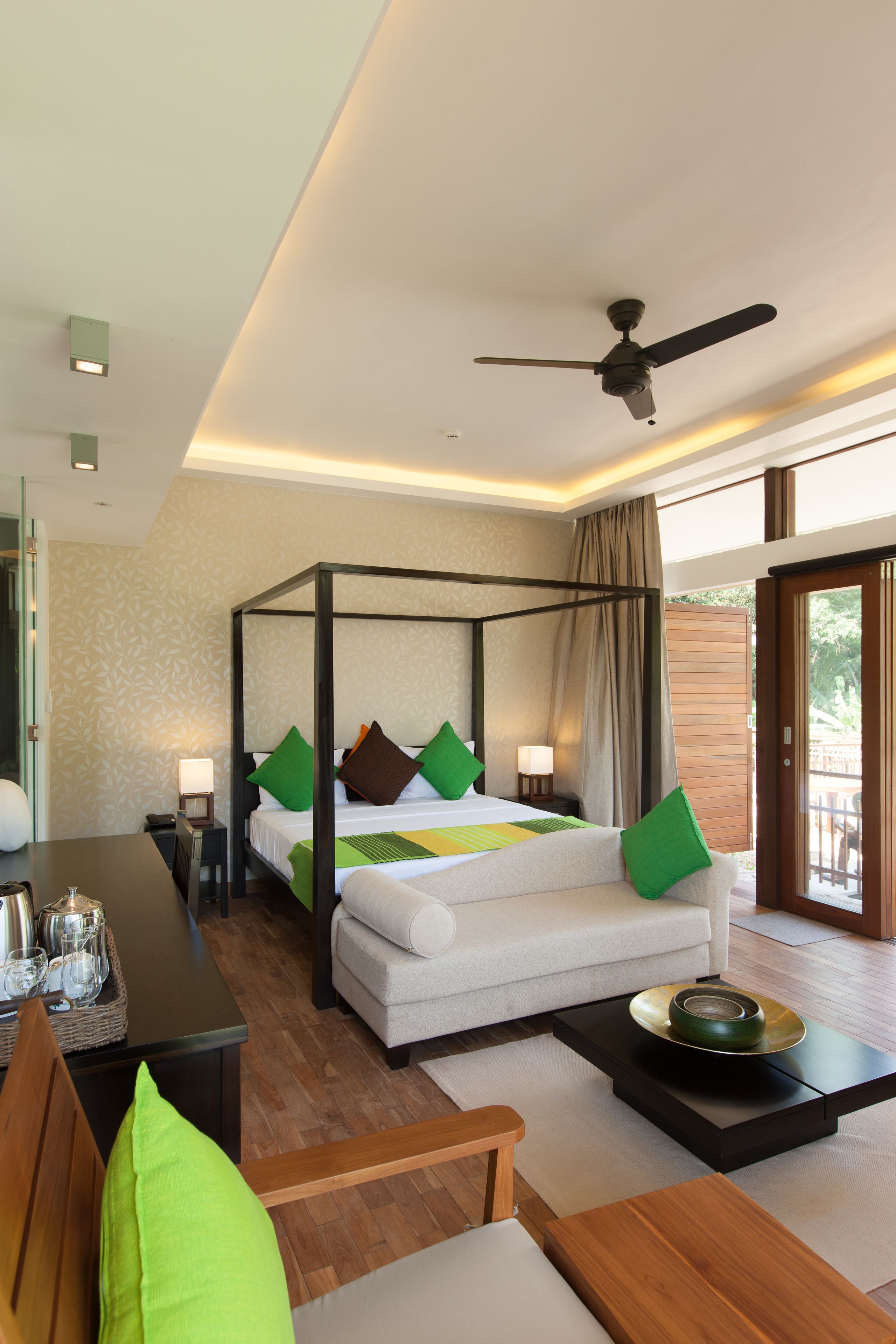 A modern hotel room with a four-poster bed, a dining table, and a balcony with a view.