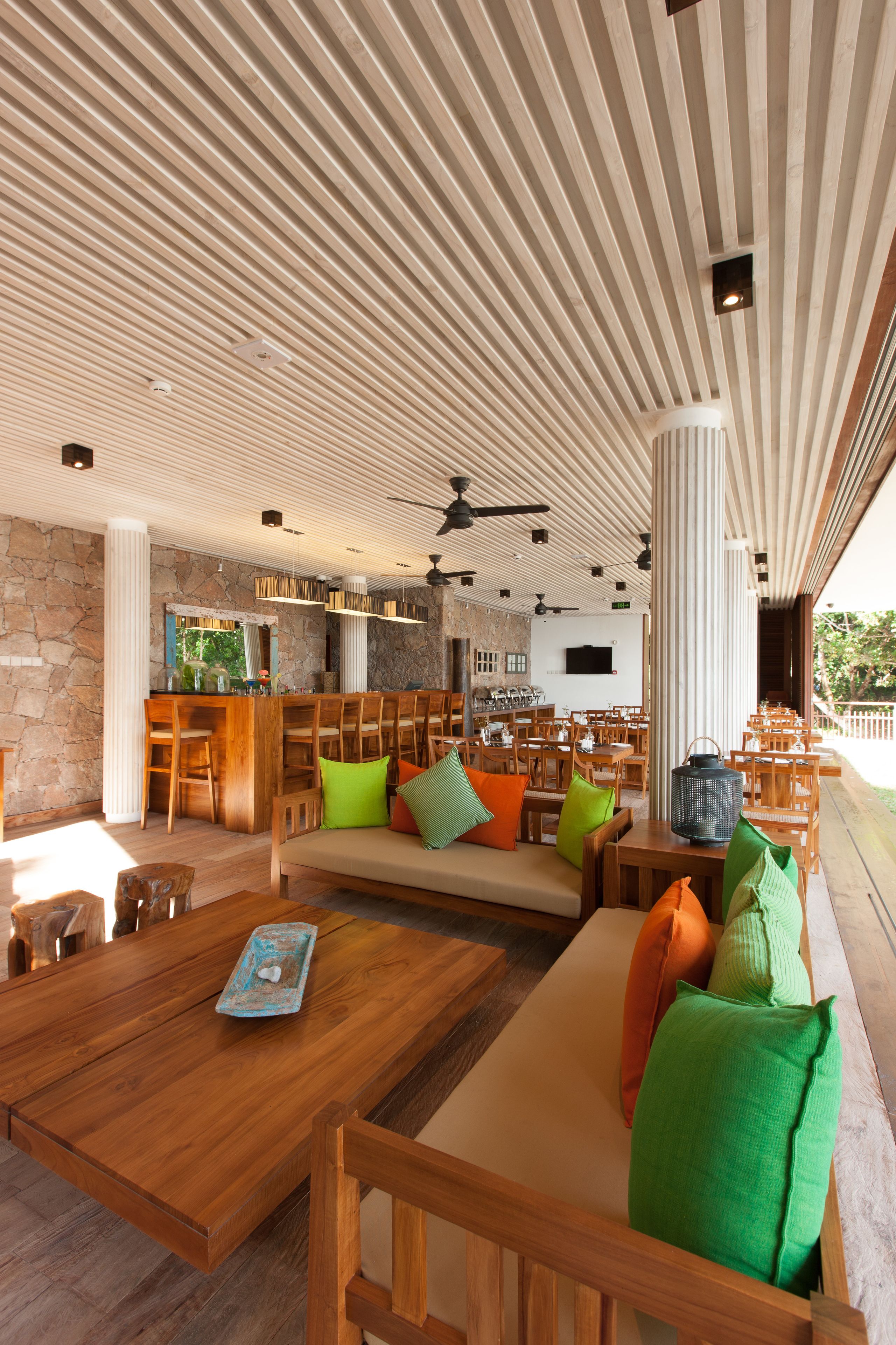Un espacio interior amplio con muebles de madera, una pared de piedra y un techo con listones de madera.