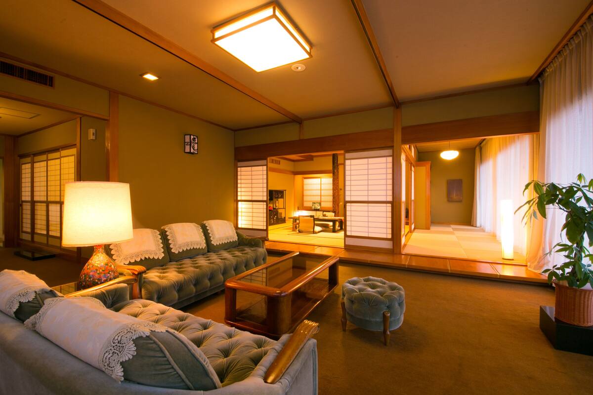 A traditional Japanese-style living room with tatami flooring, a low wooden table, and a sofa.