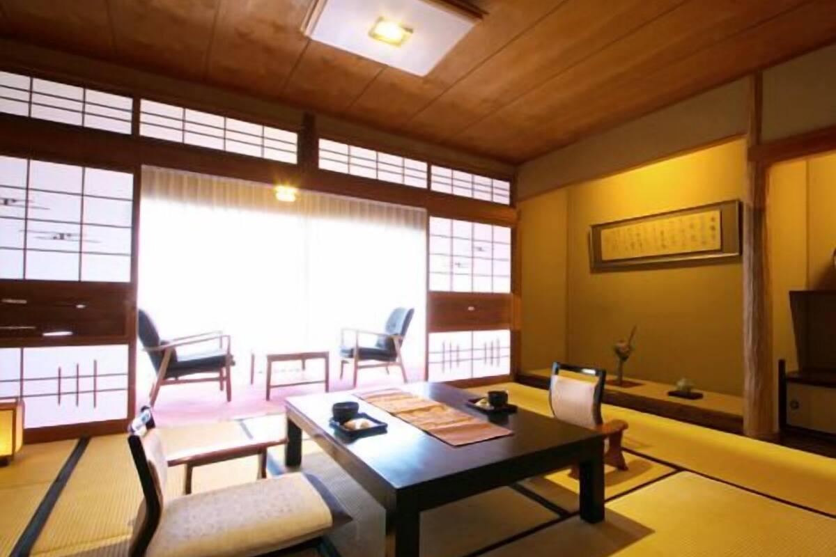 A traditional Japanese room with tatami flooring, a low table, chairs, and sliding doors.