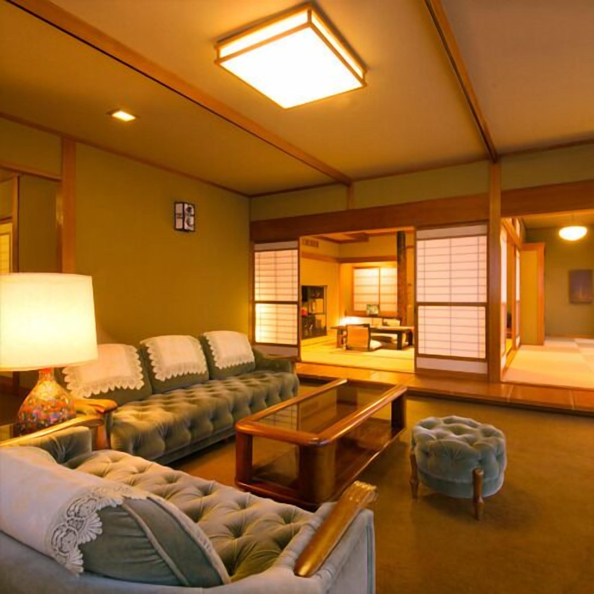 Ein traditioneller japanischer Raum mit Sofa, kleinem Tisch, Lampe und Tatami-Matte.