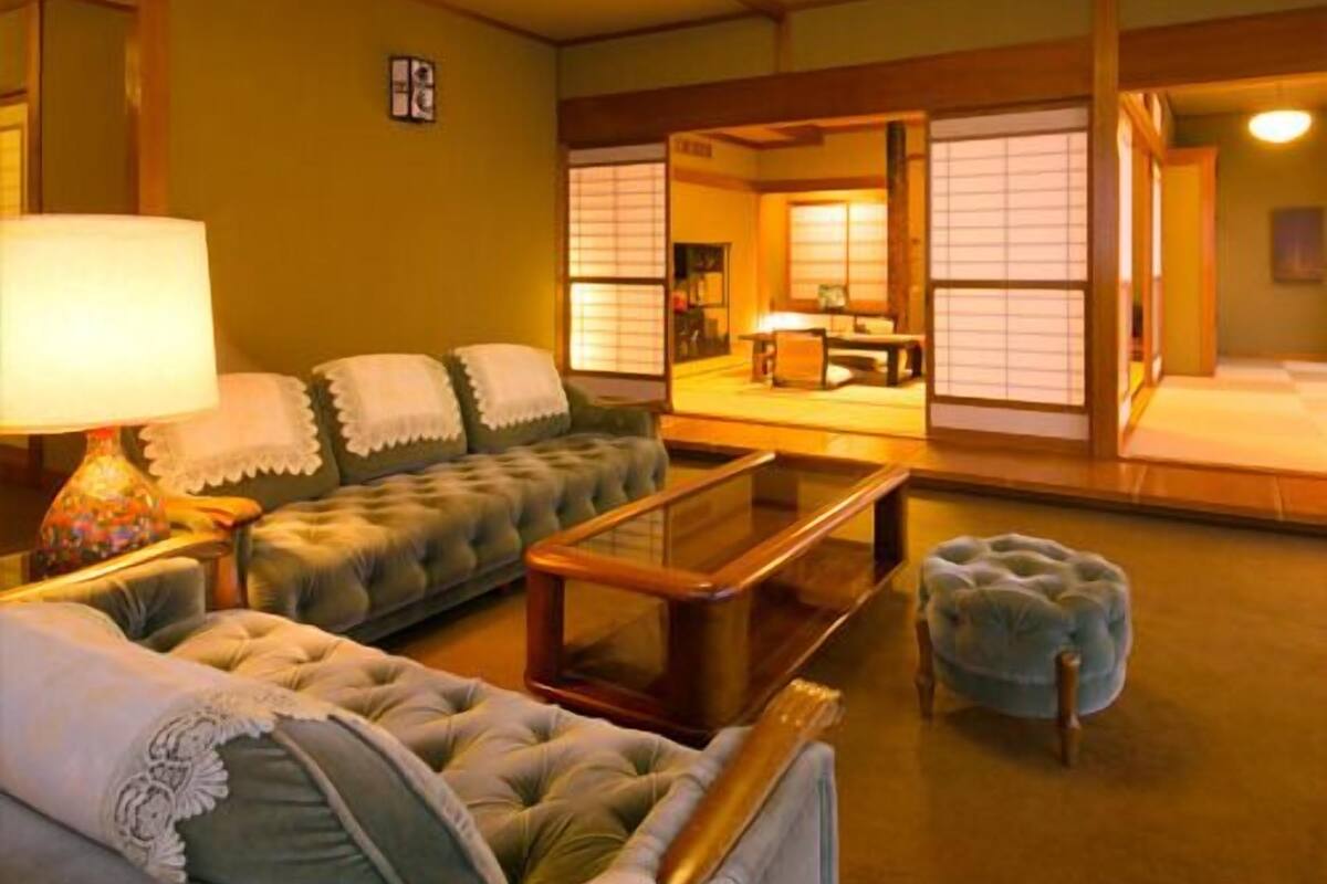 A traditional Japanese-style room with a sofa, a small table, a lamp, and a tatami mat.