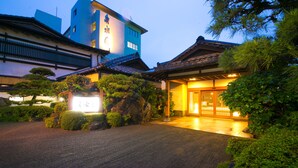 A traditional Japanese building with a tiled roof, a stone lantern, and a wooden gate. - Ibusuki Shusuien (Ibusuki)
