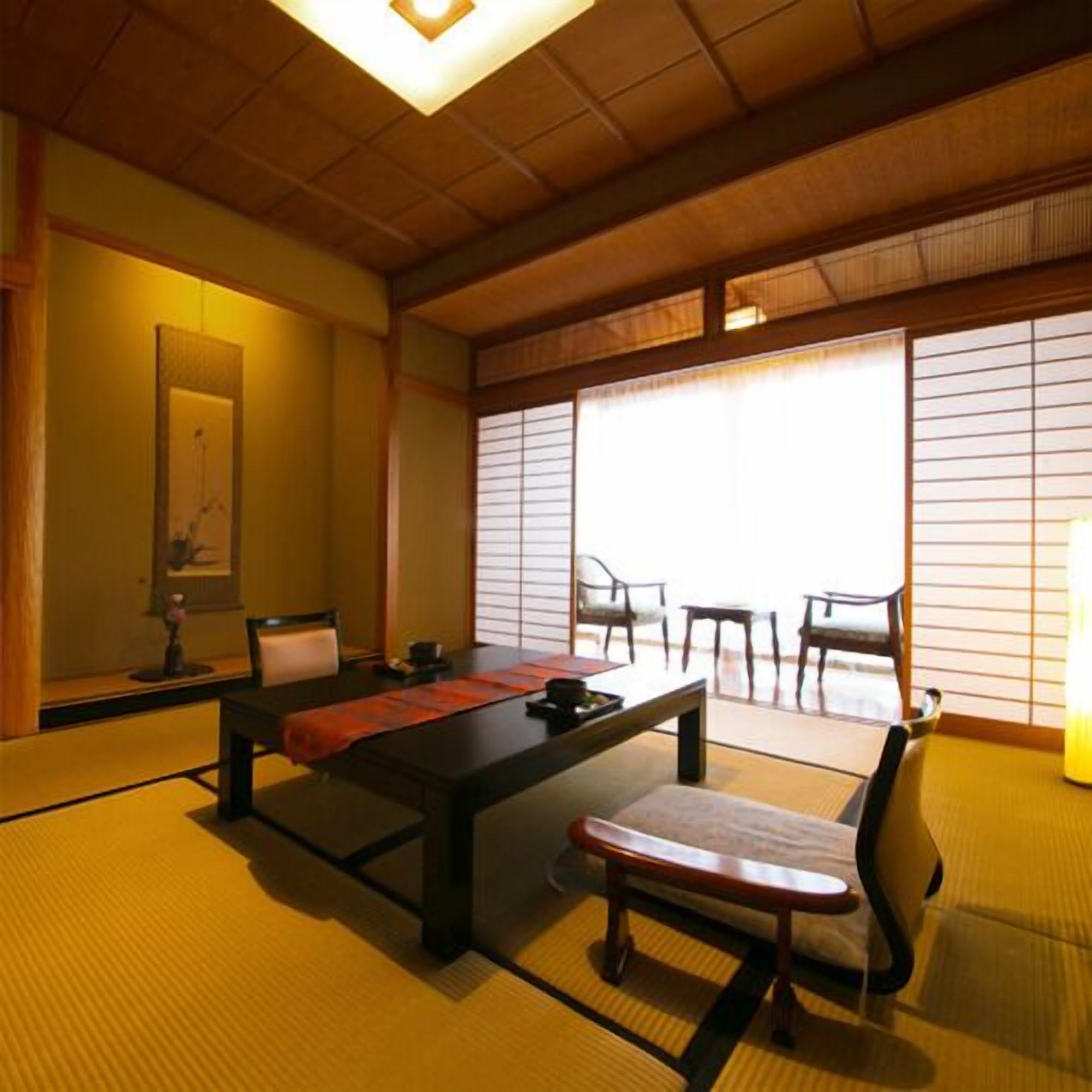 Ein traditioneller japanischer Raum mit Tatami-Boden, einem niedrigen Tisch, einem Stuhl und verschiebbaren Shoji-Türen.