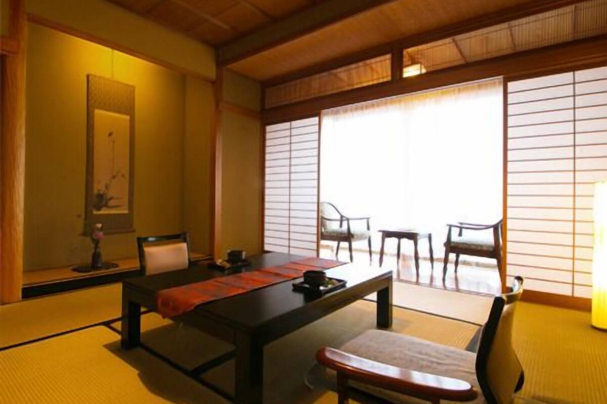 A traditional Japanese room with tatami flooring, a low table, a chair, and sliding shoji doors.