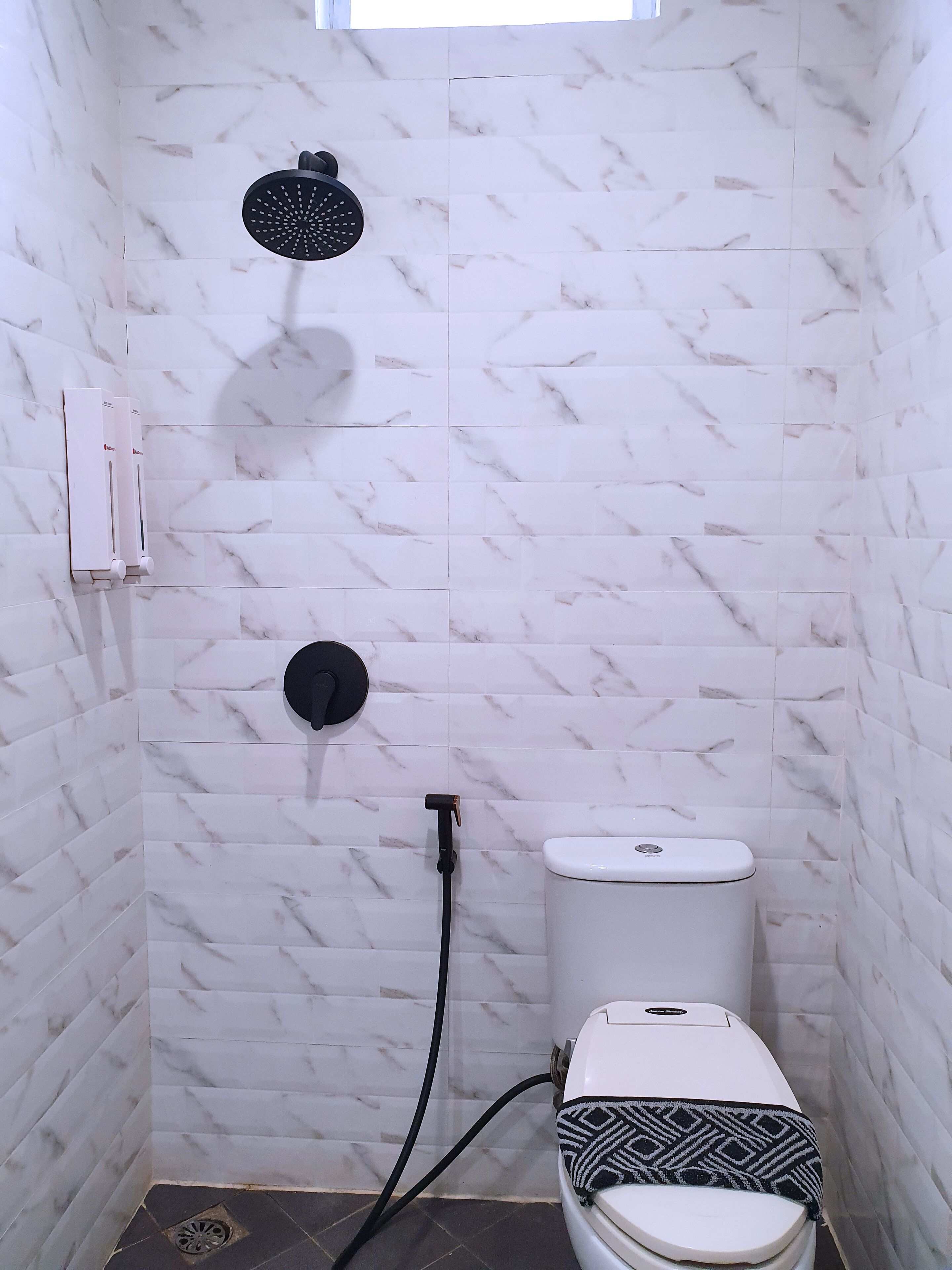 A bathroom with a toilet, a shower, and a hand dryer.