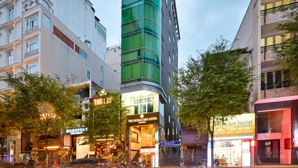 A hotel with a prominent sign at the top, multiple floors, and a modern glass facade. - The Noble Swan Hotel New World (Ho Chi Minh City)