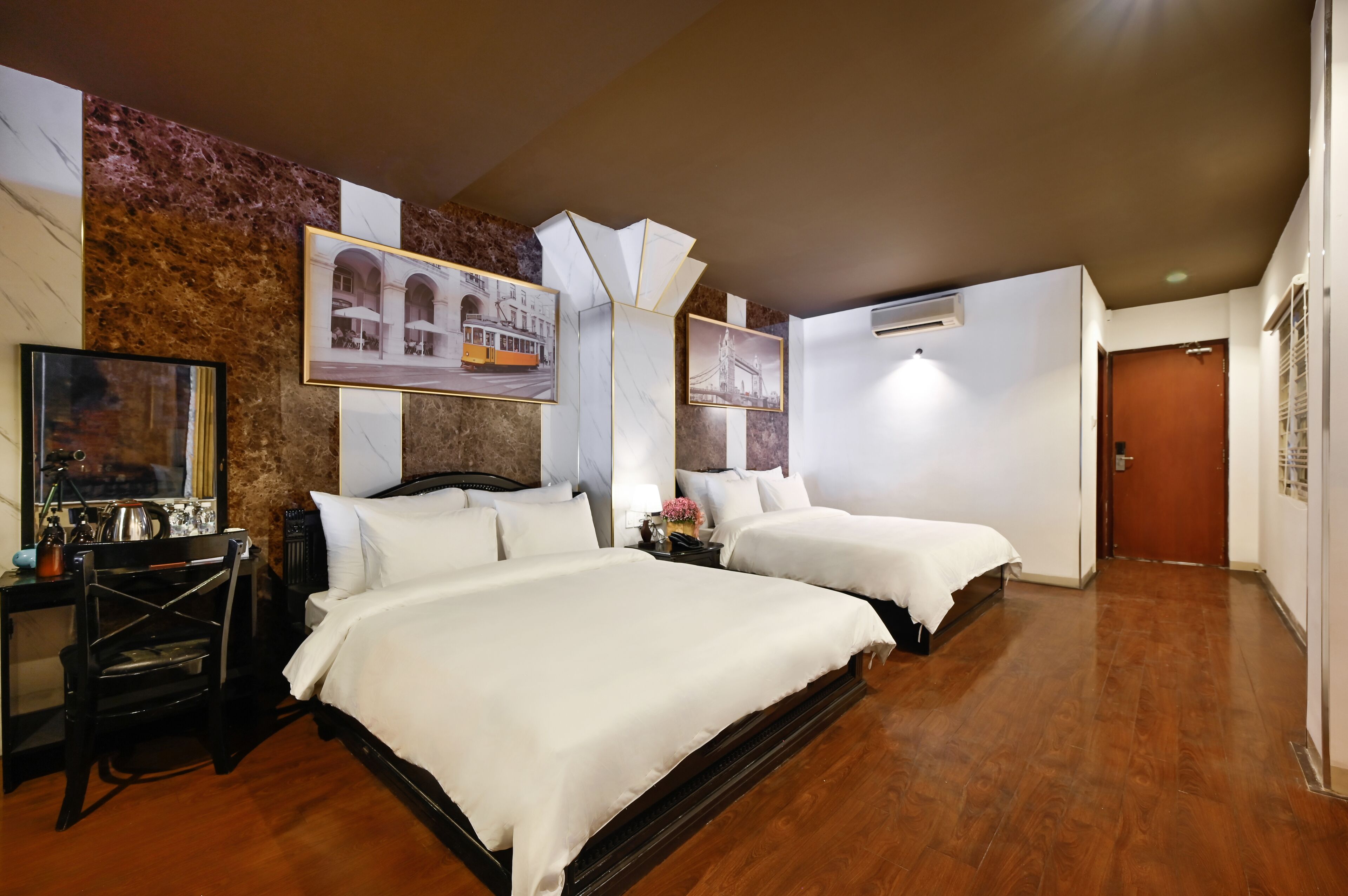 A hotel room with two beds, a desk, a chair, and a large mirror.