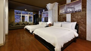 A hotel room with two beds, a sofa, a large window, and a framed picture of a bridge. - The Noble Swan Hotel New World (Ho Chi Minh City)