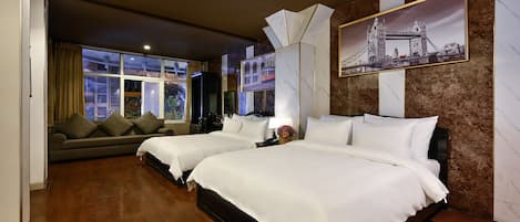 Habitación de hotel con dos camas, un sofá, un ventanal grande y un cuadro con una imagen de un puente.