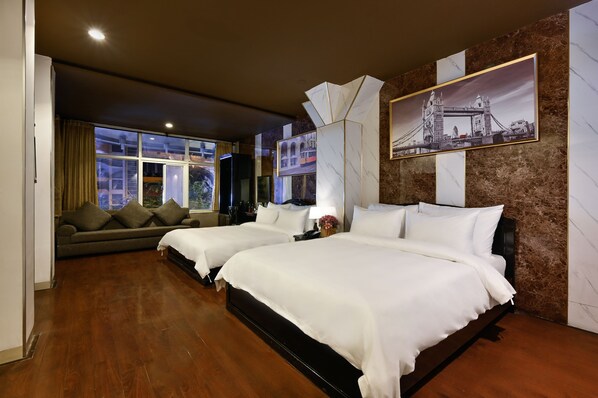 A hotel room with two beds, a sofa, a large window, and a framed picture of a bridge.