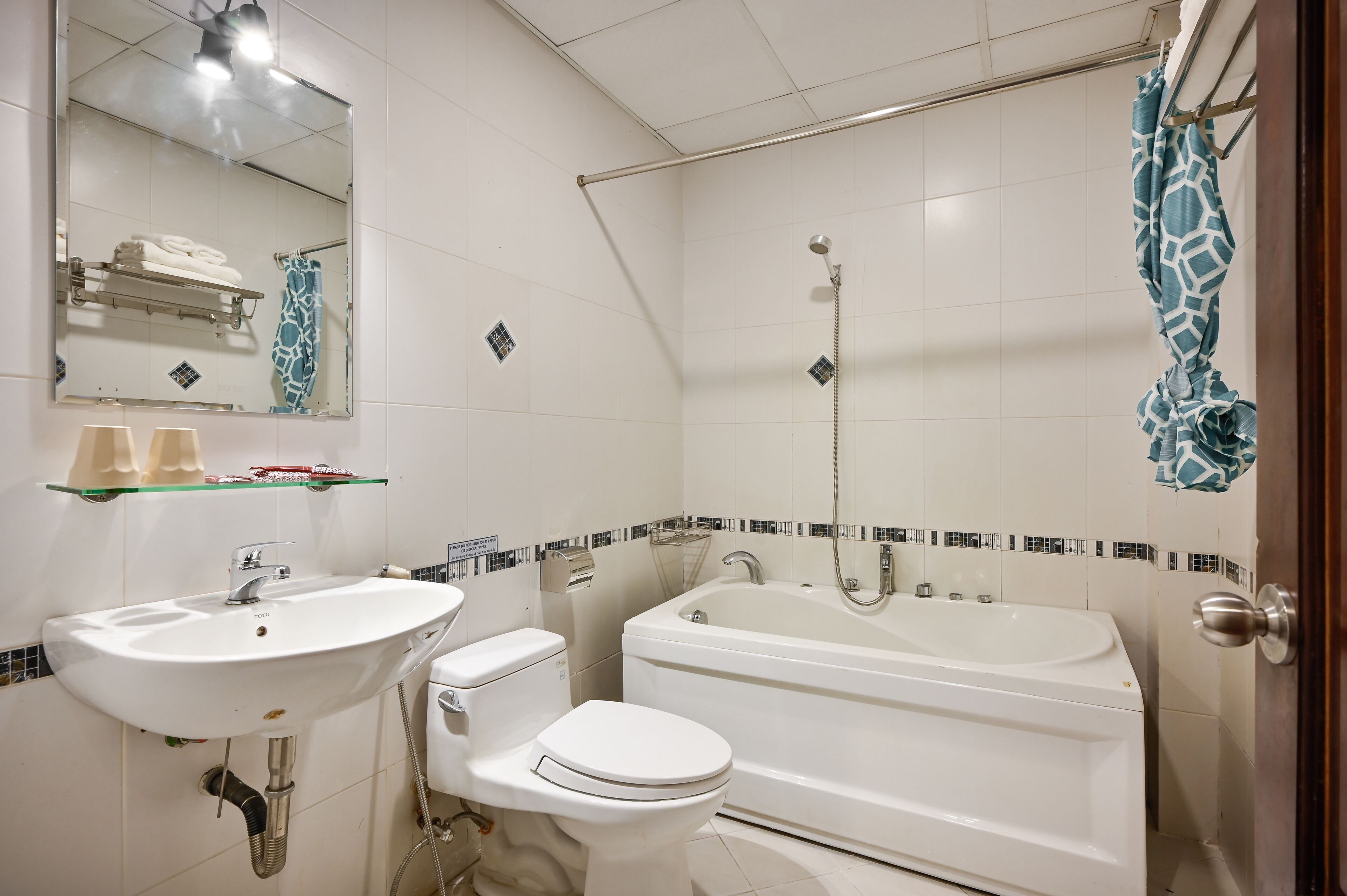 A bathroom with a white sink, toilet, and bathtub. There is a towel rack above the sink and a shower curtain with a giraffe pattern.