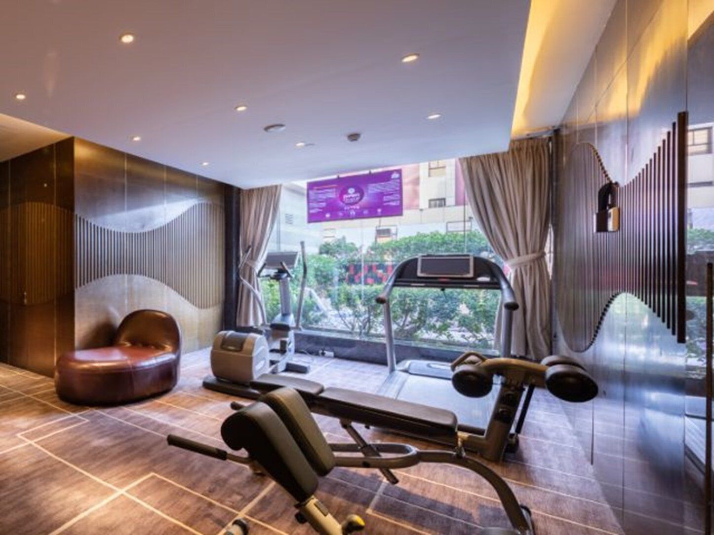 A modern gym with exercise equipment, a large window, and a view of the outdoors.