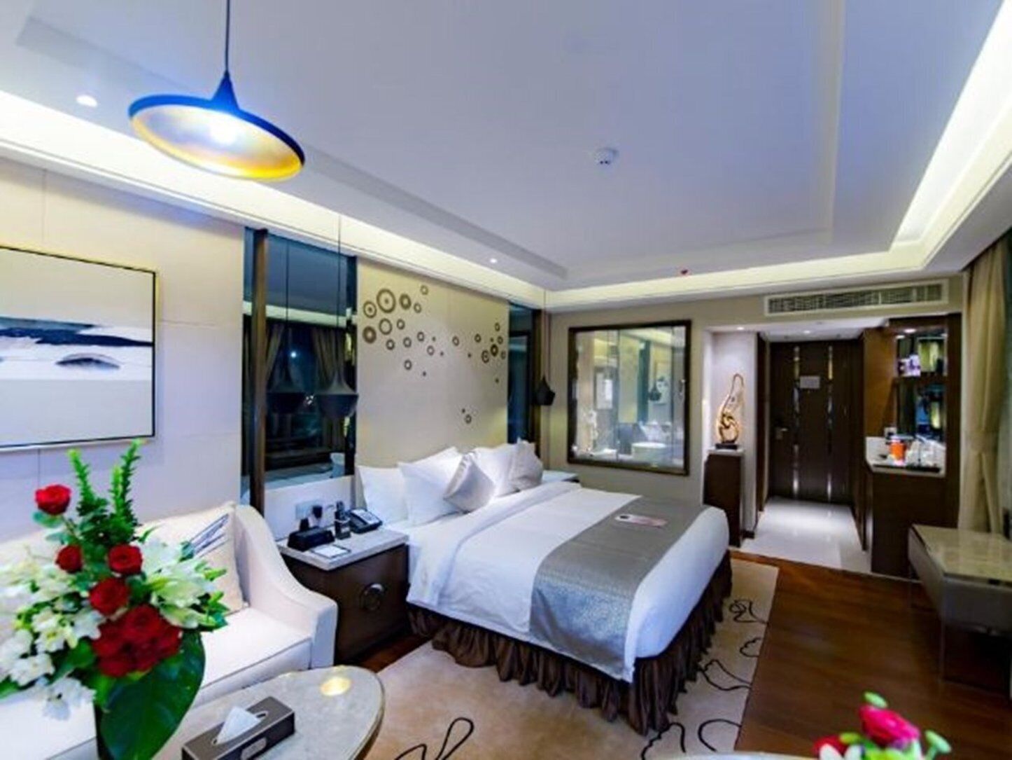 A modern hotel room with a bed, bedside table, and a large window.