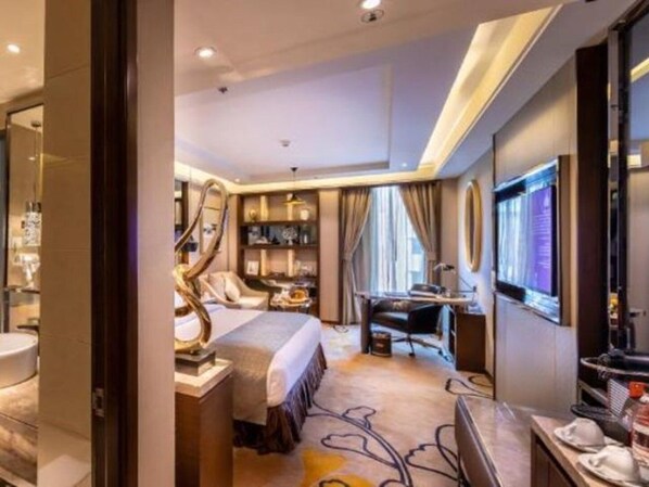Una habitación de hotel con una cama, un escritorio, una silla, un televisor y un baño.