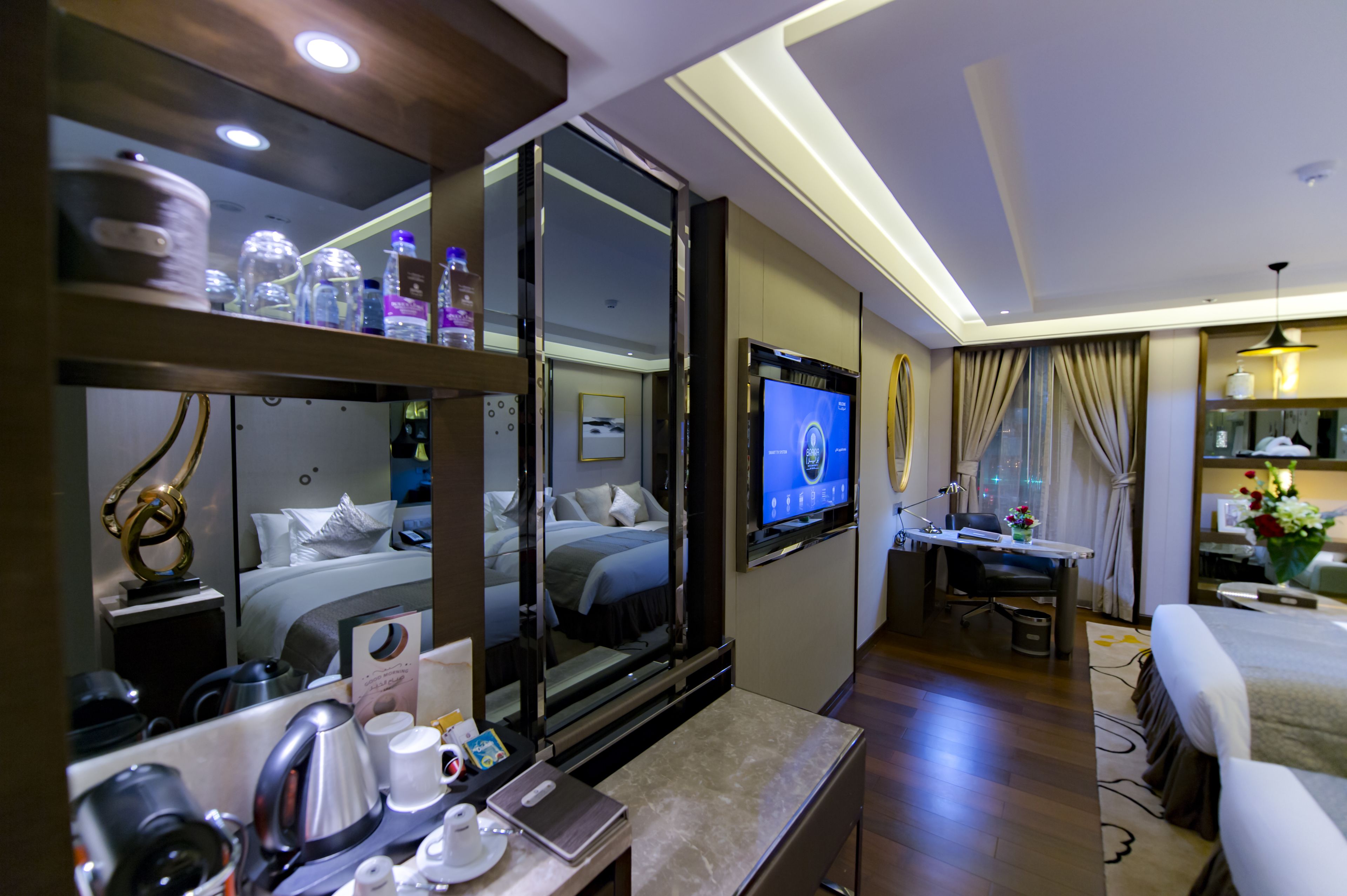 A hotel room with a bed, a desk, a TV, and a mirror.