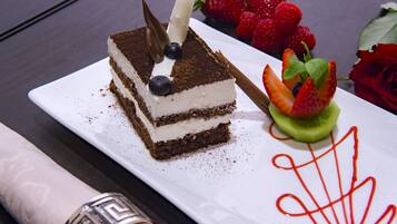 A slice of layered cake with strawberries and a rose on a white plate.