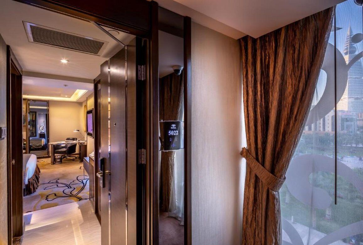 A hotel room with a large window, a bed, a desk, and a bathroom.