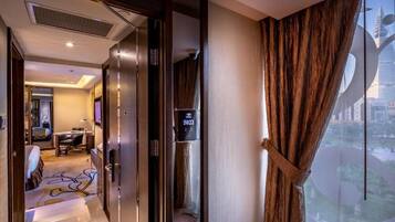 A hotel room with a large window, a bed, a desk, and a bathroom.