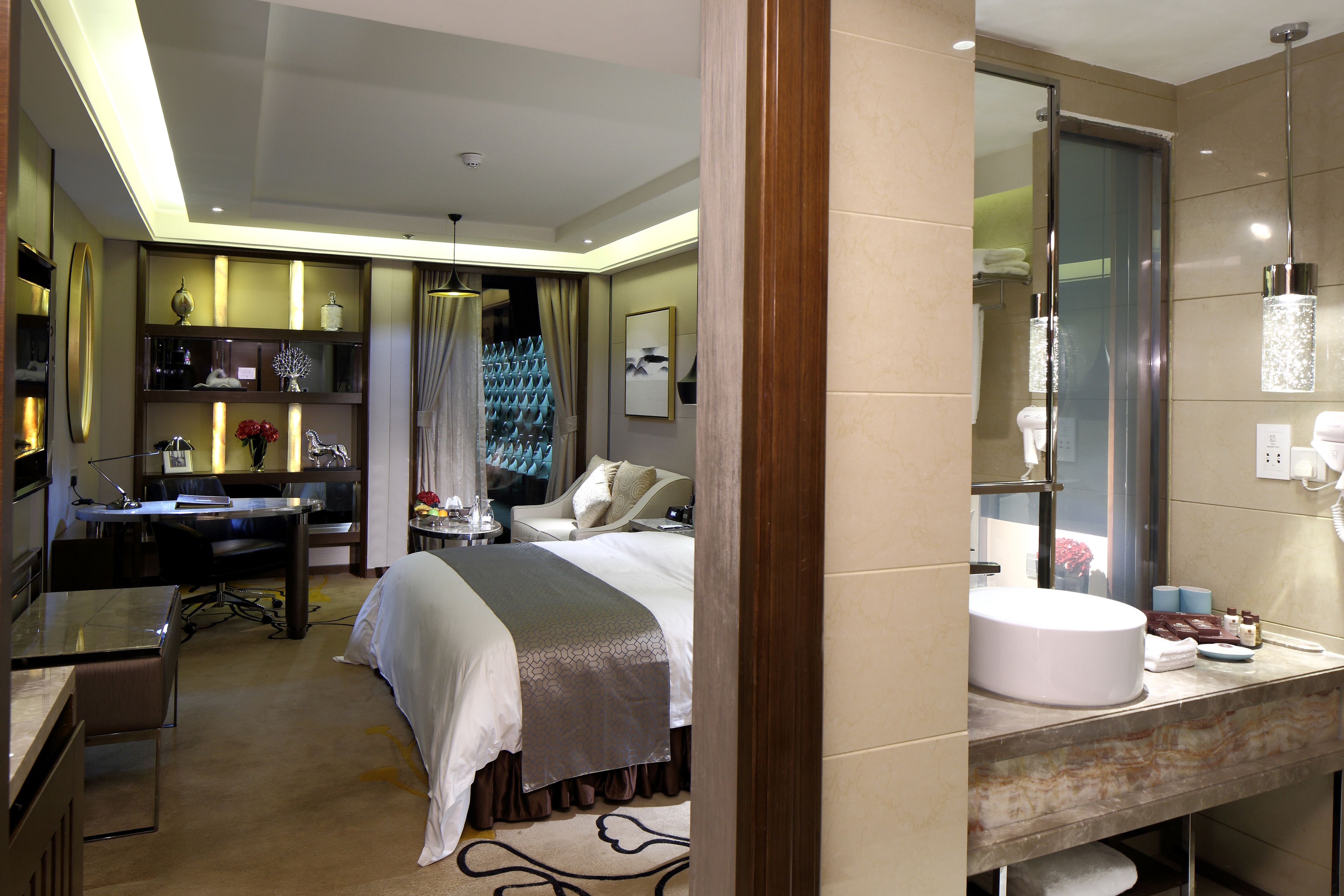 Una habitación de hotel moderna con cama, escritorio y un espejo de baño grande.