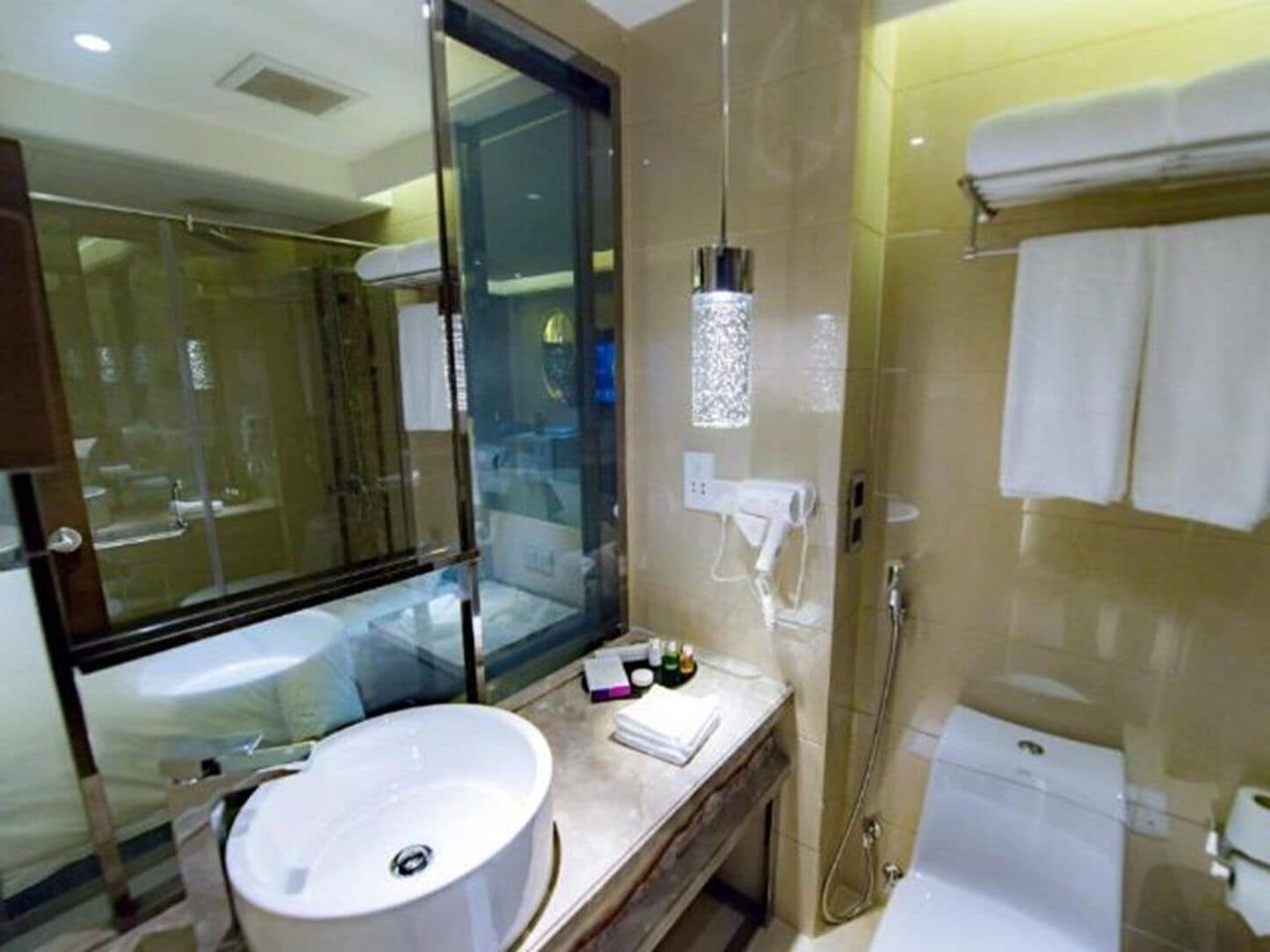 A modern bathroom with a large mirror, a sink, a shower, and a toilet.