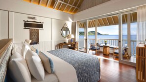 A bedroom with a large bed, a desk, and a view of the sea. - Sudamala Resort, Seraya, Flores (Labuan Bajo)