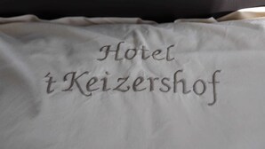 Un oreiller sur lequel est brodé le texte « Hotel Keizershof ».