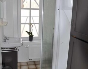 Ein Badezimmer mit einem weißen Waschbecken, einer Topfpflanze und einem Fenster mit Blick.