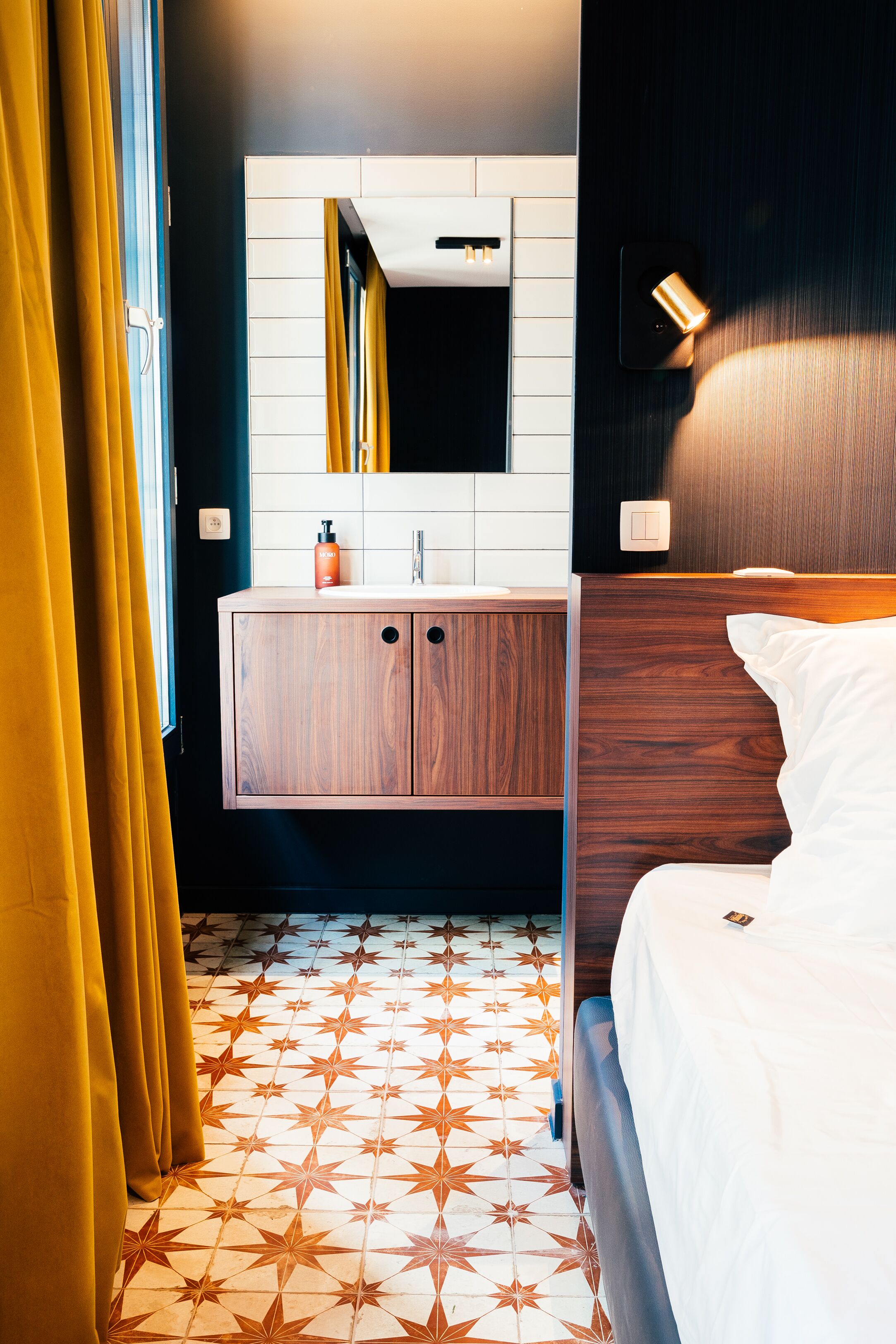 A hotel room with a wooden wardrobe, a white bed, and a star-patterned floor.
